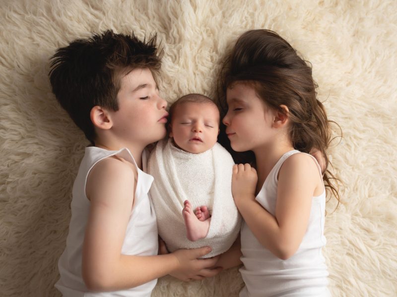 newborn-baby-laying-between-her-brother-and-sister